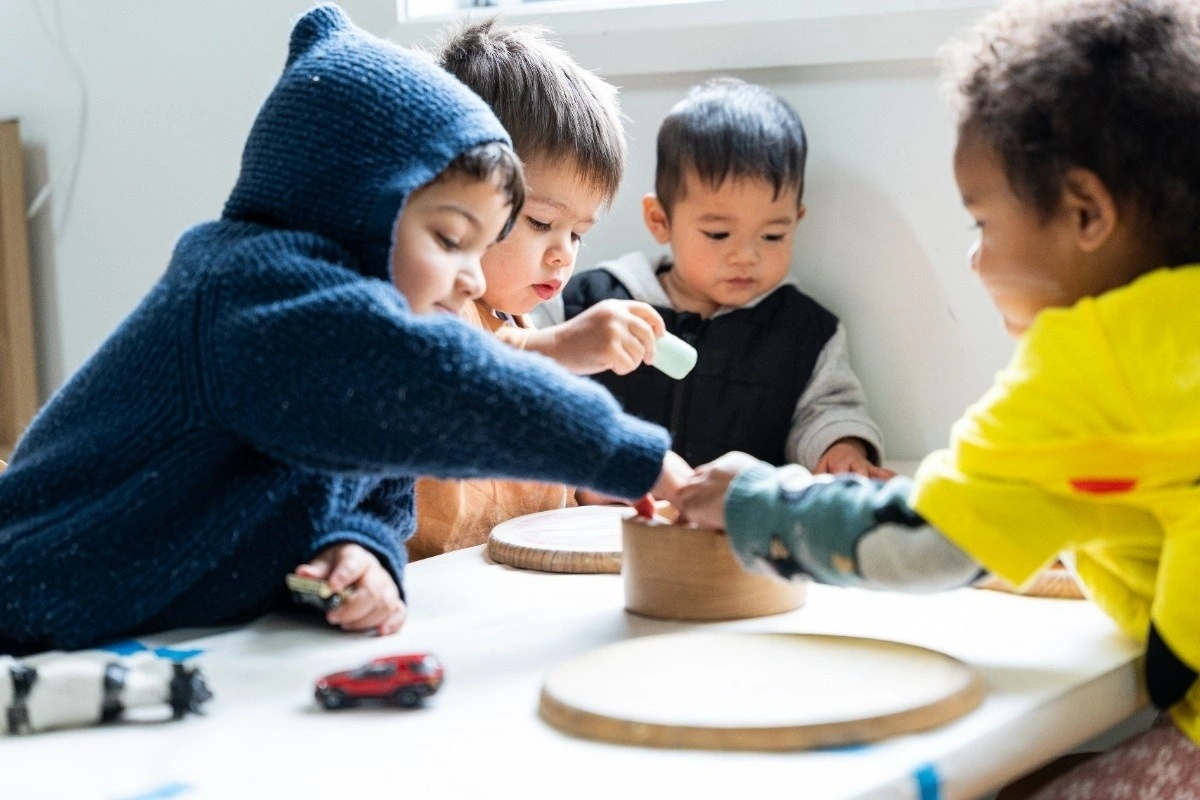 Toddlers playing with wooden toys in a nursery setting.